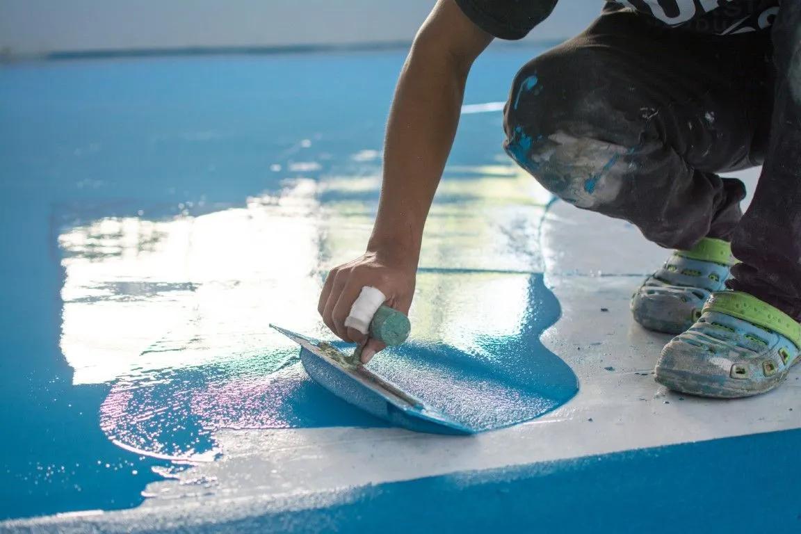 Close-up of blue epoxy coating being applied to a garage floor